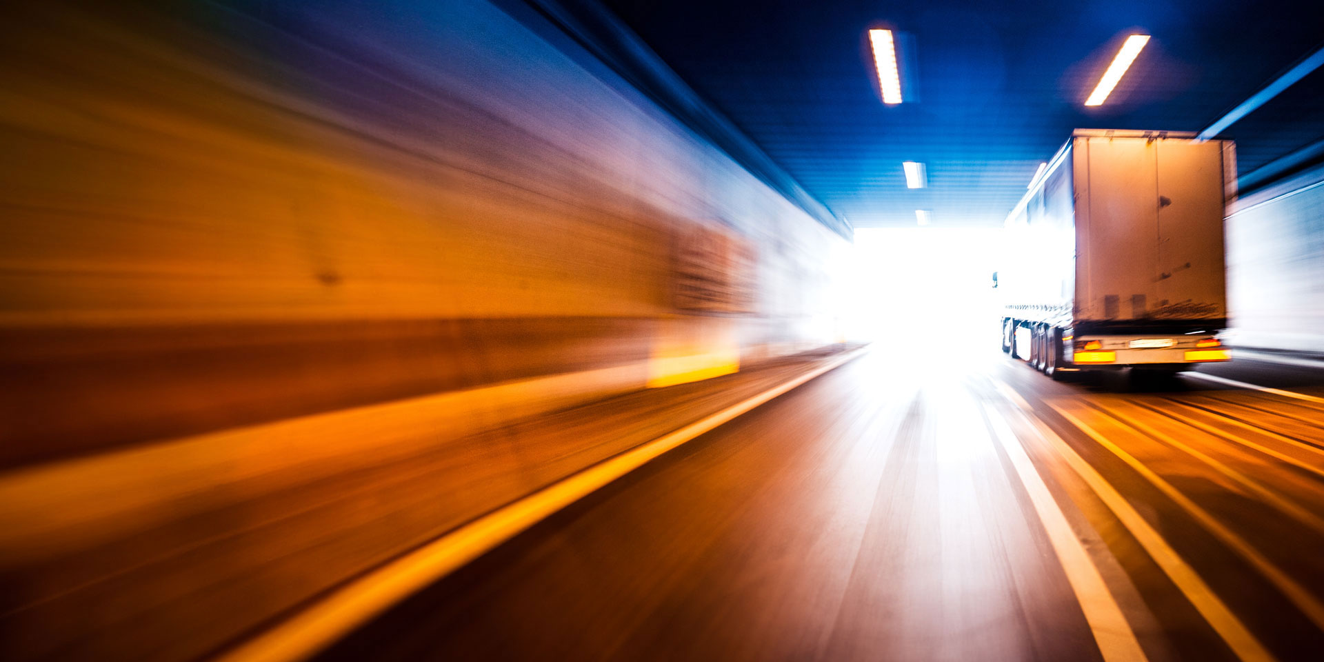 Timelapse of a semi truck traveling through a tunnel at night as it makes a final mile delivery