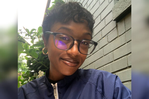 McClay's Logistics accounts payable supervisor, Sydney Eaton sitting outside on a sunny day She's wearing glasses and a navy pullover jacket.